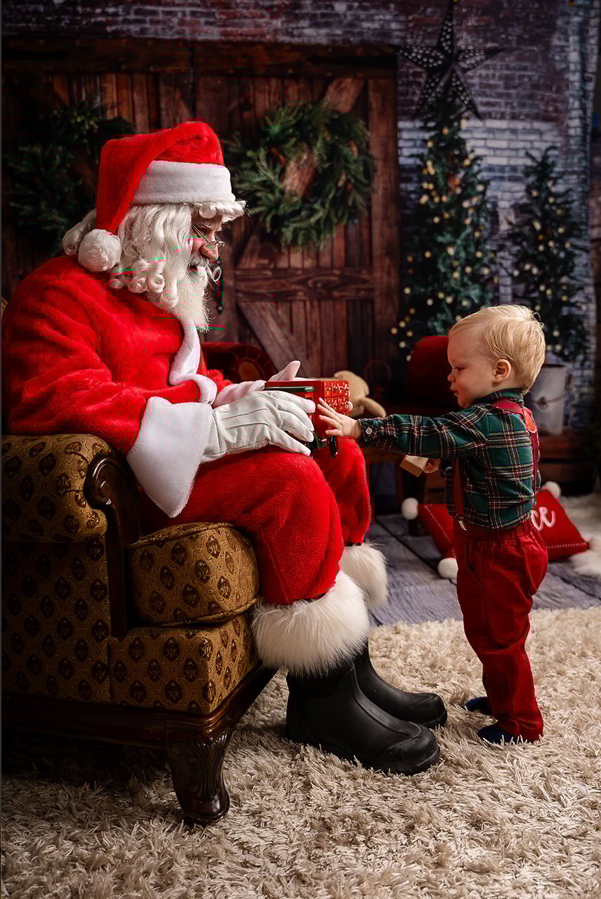 Child offers a toy truck to Santa during an interactive, sensory-friendly studio warm-up.