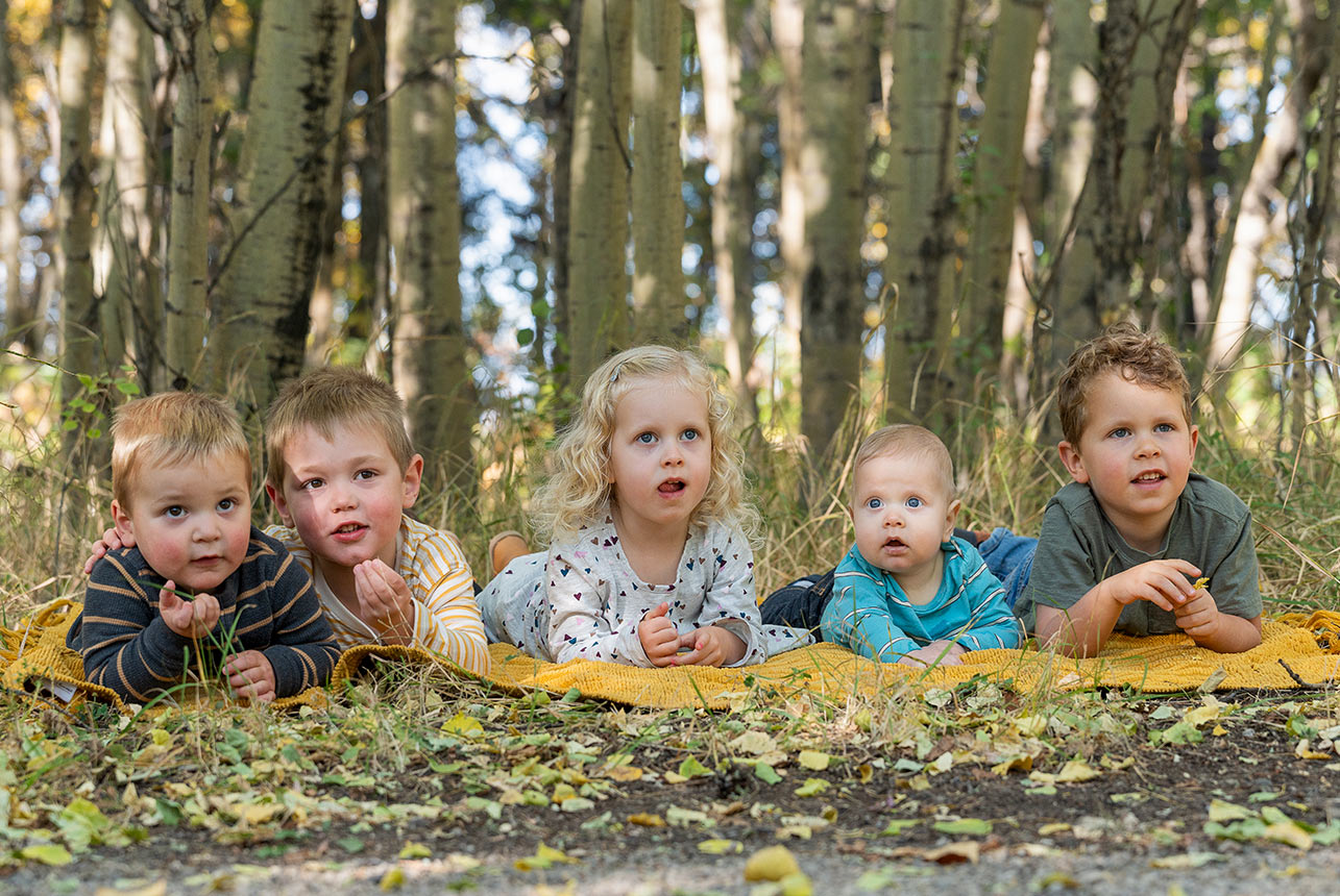 Young cousins and grandchildren lying together on a blanket during an outdoor family photo session