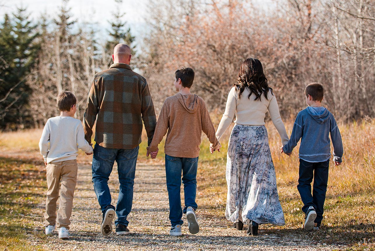 Parents and children walking hand in hand along a trail during a relaxed Edmonton area family photography session