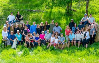 Large multi generational family gathered outdoors on hay bales during a relaxed reunion style photo session