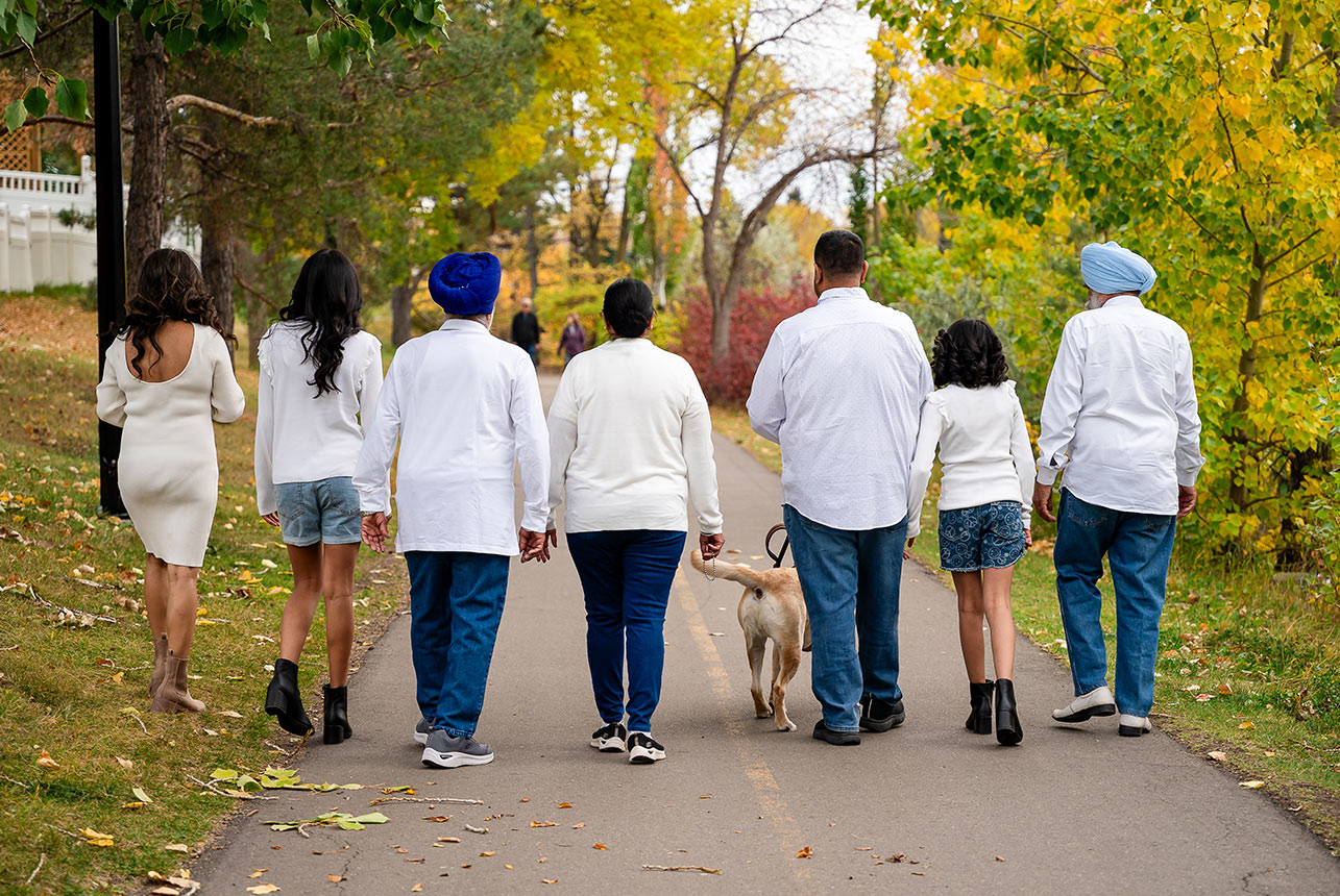 Multi generational family walking together along a tree lined path during a fall photo session