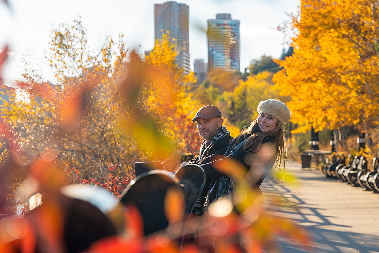 Couple relaxing together during an autumn engagement session with the Edmonton skyline in the background