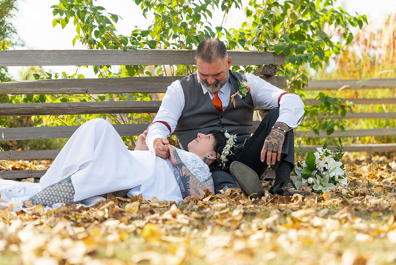 Trudy and Byron lying together in autumn leaves during their wedding portraits.