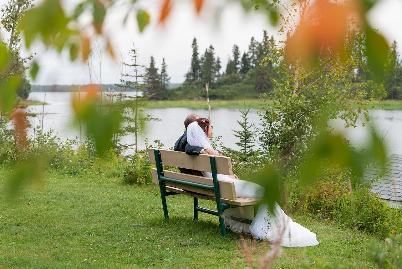 Bride and groom sitting together by the lake after their Elk Island National Park wedding